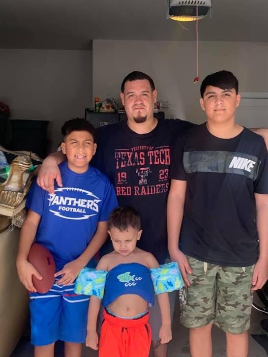 Family members stand together in a living room, smiling and enjoying their time together.