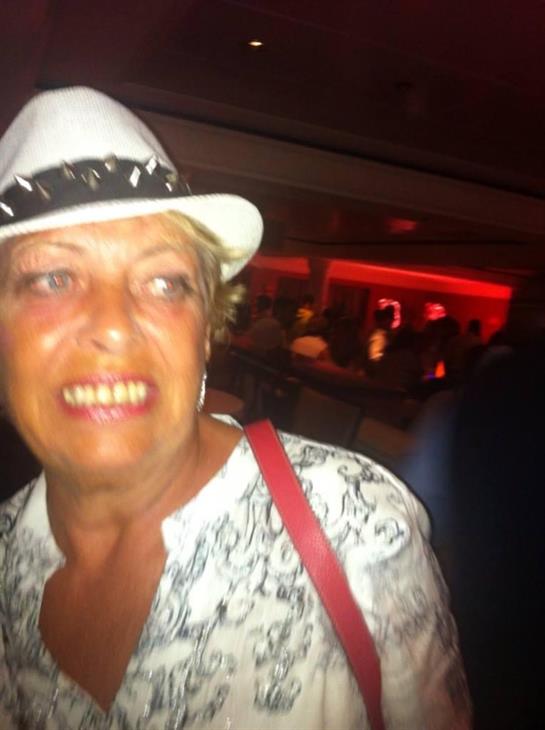 A woman in a white hat and patterned blouse enjoys a lively, warmly lit scene.