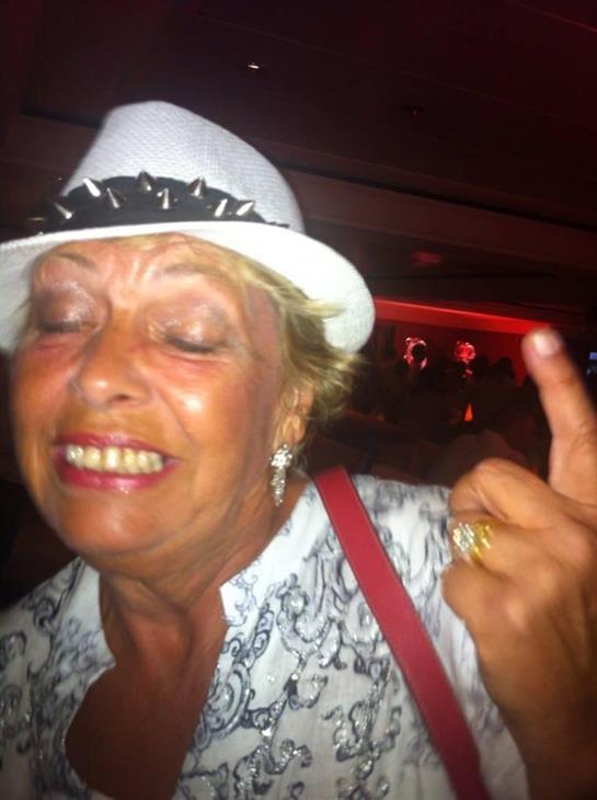 A cheerful woman with a hat celebrates at a dimly lit nightclub, expressing joy and fun.