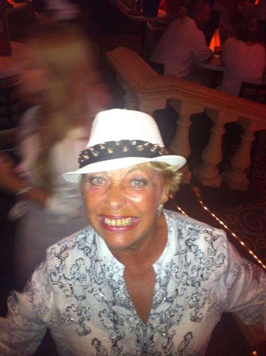 A cheerful woman enjoys a festive atmosphere, wearing a stylish white hat and smiling broadly.