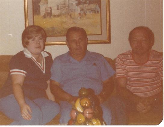Three individuals pose in a cozy living room, showcasing a decorative painting and statue.