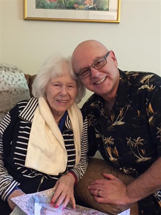 Two people share a joyful moment in a comfortable living space, smiling and embracing each other.