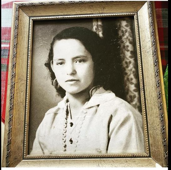 A young girl poses for her portrait, showcasing a classic hairstyle and a pearl necklace.