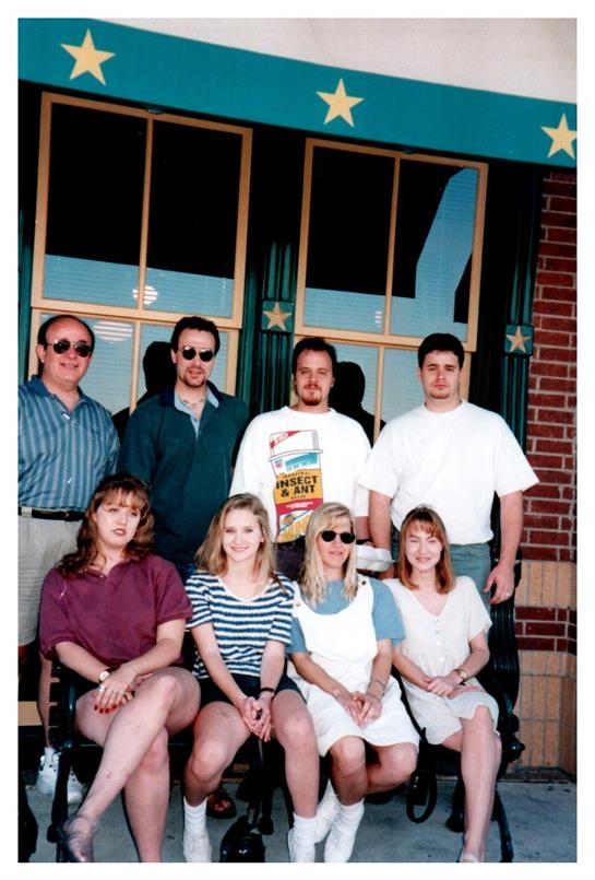 A group of friends enjoys a sunny afternoon outside a brick building.