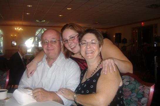 Three family members share a happy moment at a restaurant, enjoying each other's company.
