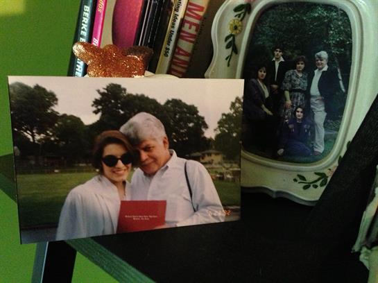 A happy couple poses together in a park while holding a book, surrounded by personal belongings.