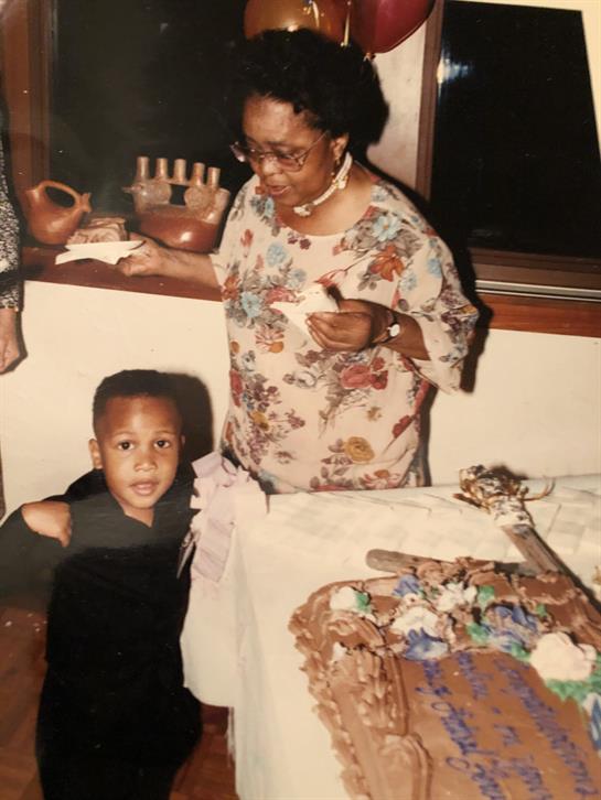 An elder woman shares food with family while a child enjoys the festive atmosphere around them.