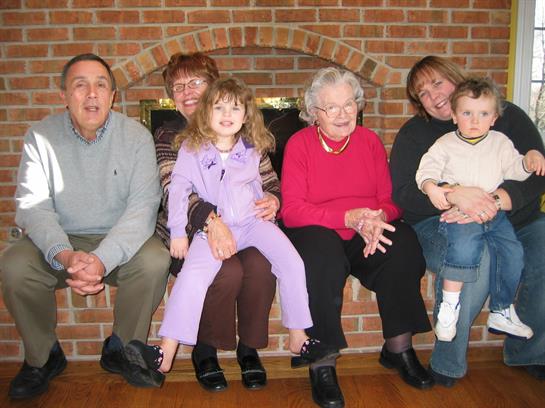 Family members enjoy time together by the fireplace, sharing smiles and laughter during a gathering.