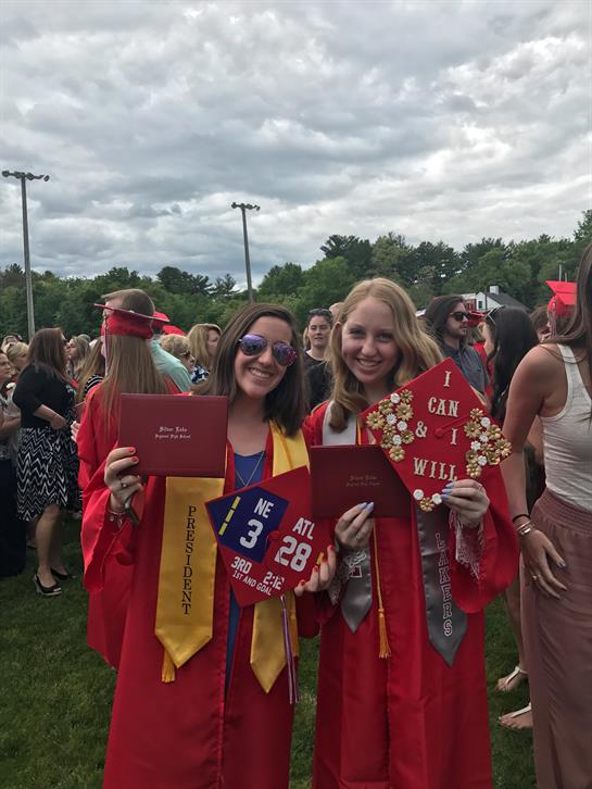 Friends celebrate their graduation, proudly displaying diplomas and vibrant decorations in the park.