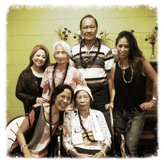 A joyful family of six across generations celebrates together in a colorful room.