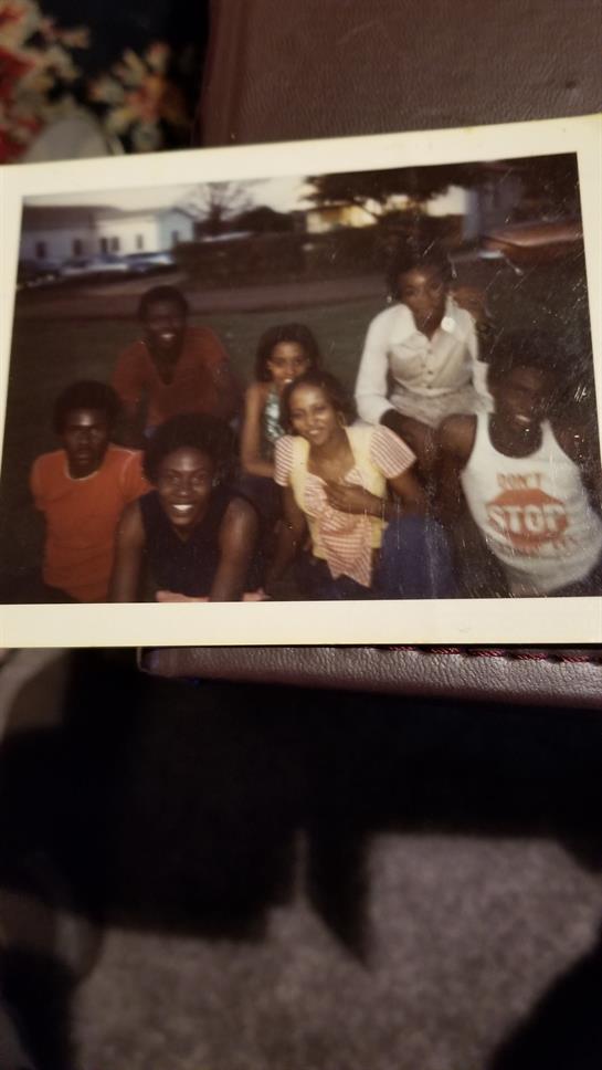 Friends pose with smiles, enjoying a fun moment together in the park during sunset.