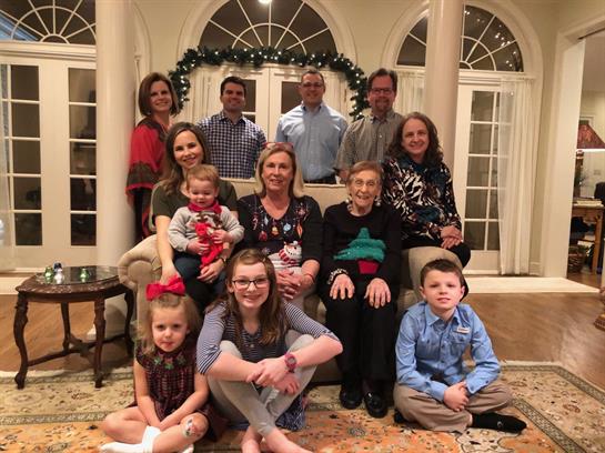 A large family enjoys each other’s company in a decorated living room at holiday time.