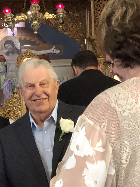 Family members gather in a church, celebrating a wedding as the groom's grandfather smiles warmly.