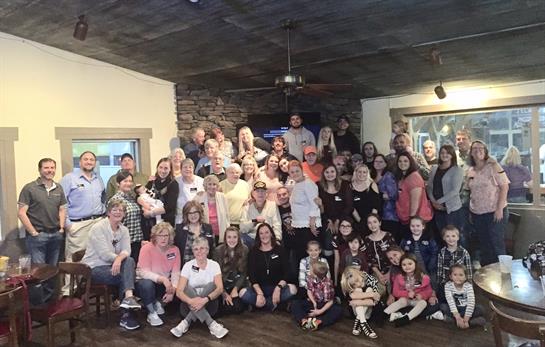 Large group of people celebrating together in a cozy, rustic space with cheerful vibes.