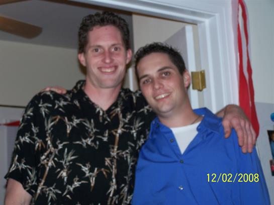 Two friends pose together with big smiles during a relaxed home gathering at night.