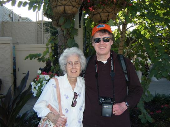 Two individuals enjoy a cheerful moment in a vibrant garden, surrounded by flowers and plants.