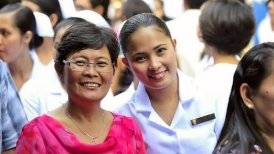 Two women pose for a joyful moment during a special graduation event surrounded by guests.