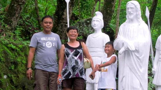 A group of four enjoys their time in a lush garden, posing next to artistic white statues.