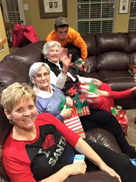 Relatives enjoy a cozy celebration, exchanging gifts and sharing smiles in a warm living room.