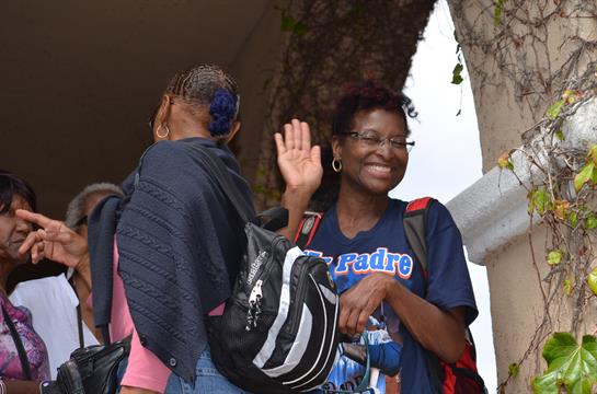 Friends gather under a tree, sharing laughter and greetings during a joyful moment outside.