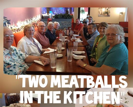 A cheerful group of seniors sits around a large table, enjoying each other's company while dining.
