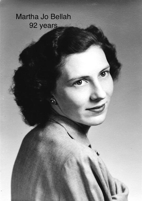A young woman with curly hair poses gracefully for a portrait in a studio setting.