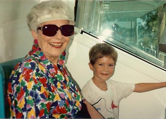 A cheerful senior woman in colorful clothing shares a happy moment with her young grandson.