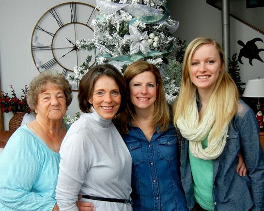 Four women from different generations joyfully celebrate the holidays by a lovely Christmas tree.
