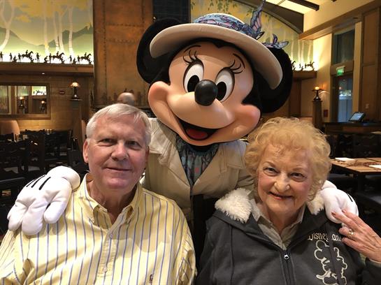 Couple shares a joyful moment with a cheerful character in a cozy restaurant.