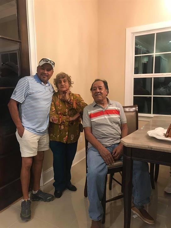 Three friends share smiles and conversation in a warm, inviting dining space at night.