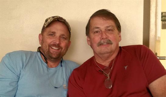 Men are smiling and sitting close together, showcasing camaraderie and friendship indoors.