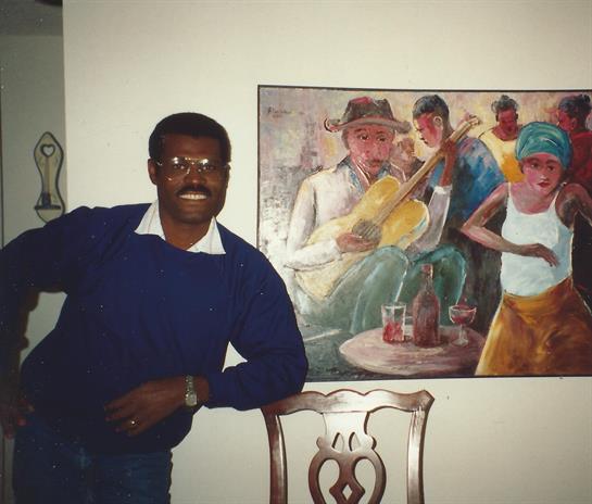 Man in a blue sweater leans against a chair, enjoying the vibrant mural of musicians and dancers.