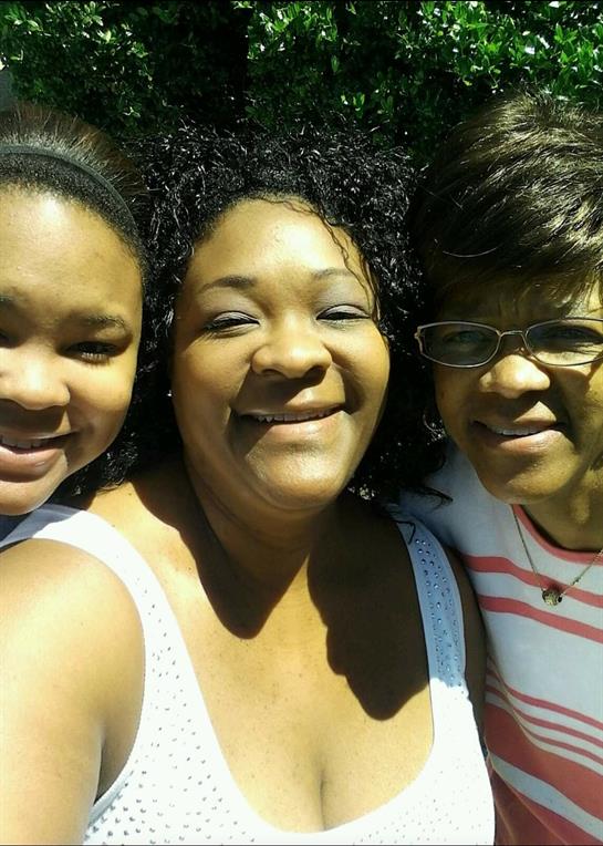 Three women smile happily while enjoying quality time together in the sunlight.