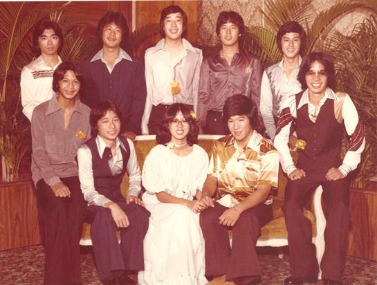 A group of young adults poses happily in stylish outfits amid a retro setting.