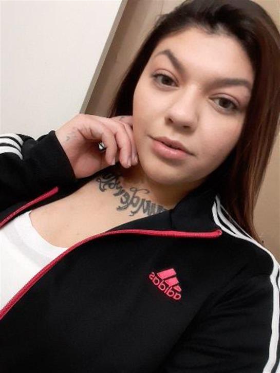 A young woman in a sports outfit smiles while showcasing her style indoors at home.