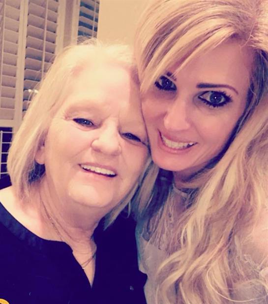 Two women smile together in a warm embrace, capturing a joyful memory during a family event.