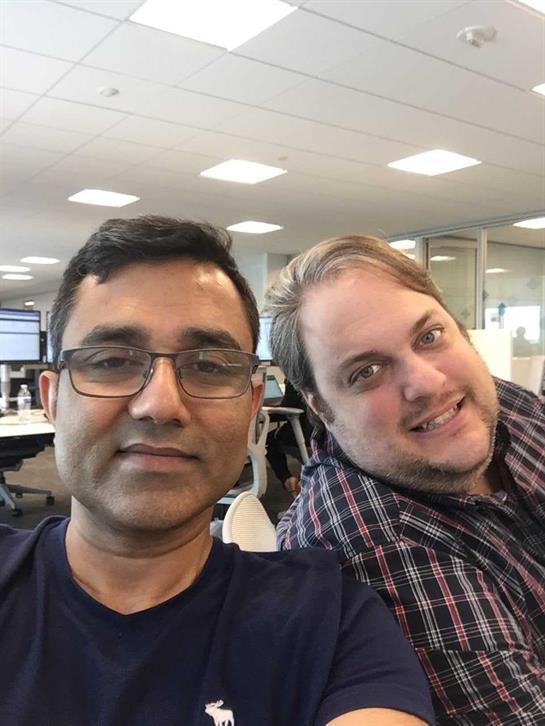 Colleagues share a joyful moment while taking a selfie in a contemporary office setting.