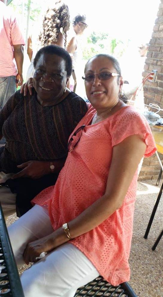 A couple seated at a table smiles warmly, enjoying the lively atmosphere of a gathering.