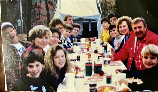 Friends gather around a long table for a joyful picnic filled with food and laughter in nature.