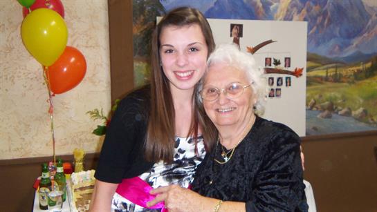 A young woman shares a joyful moment with her grandmother at a festive family gathering.