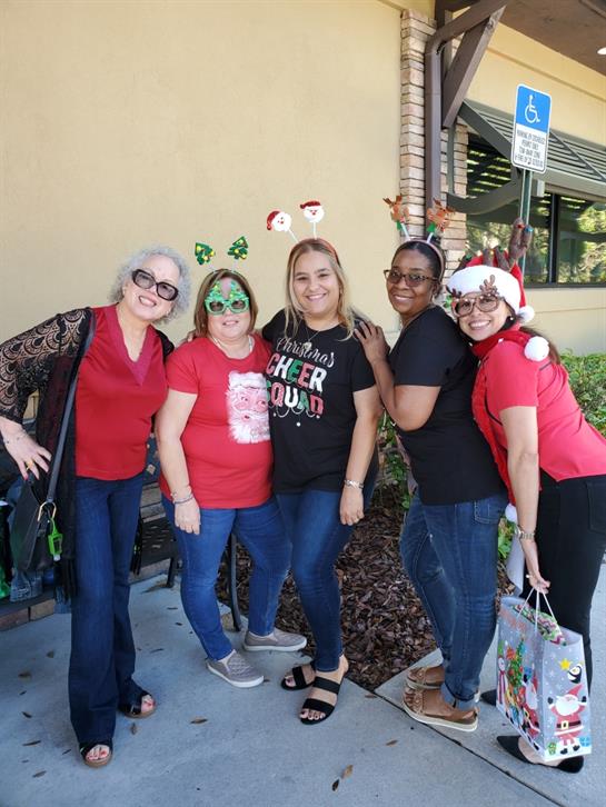 A group of friends dressed in holiday attire poses joyfully in front of a cafe during festivities.