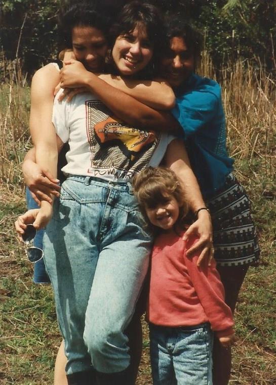 Four family members embrace joyfully while spending time together in nature.