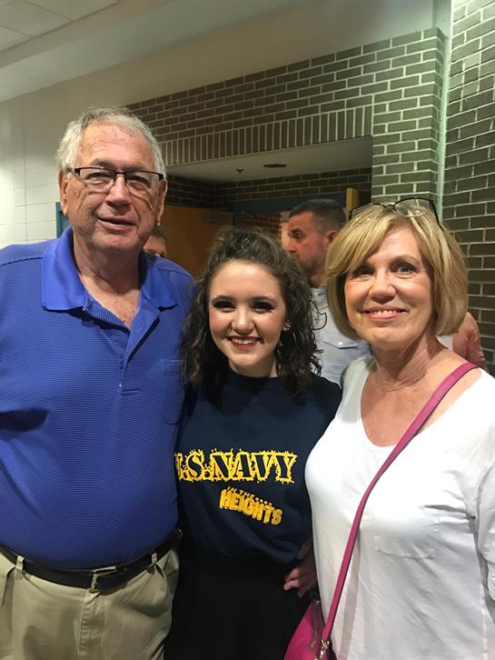 Cheerful family poses together at a school event while celebrating a talented performer.