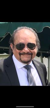 A man in formal attire enjoys the outdoors, exuding confidence while surrounded by attendees.