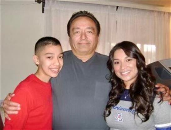 Three family members pose together happily, showcasing their close bond in a warm indoor space.