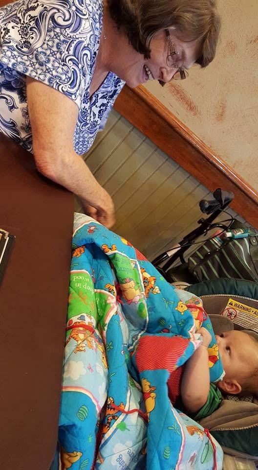 A parent shares quality time with a child wrapped in a colorful blanket at a cozy restaurant.