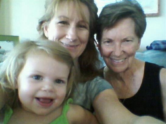 Three generations of women share a happy moment, smiling and embracing each other's presence.