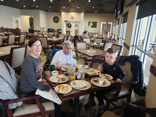 Three family members savor breakfast at a restaurant, sharing laughter and good food together.