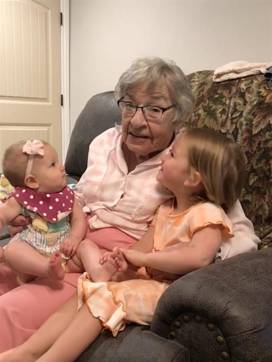 Grandmother shares a joyful moment with two girls, fostering connection and happiness at home.