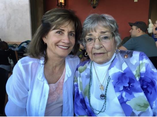 Two women smile warmly at the camera while enjoying their time in a vibrant cafe setting.